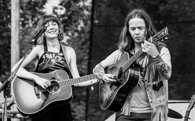 Molly Tuttle and Billy Strings standing together on an open-air stage.