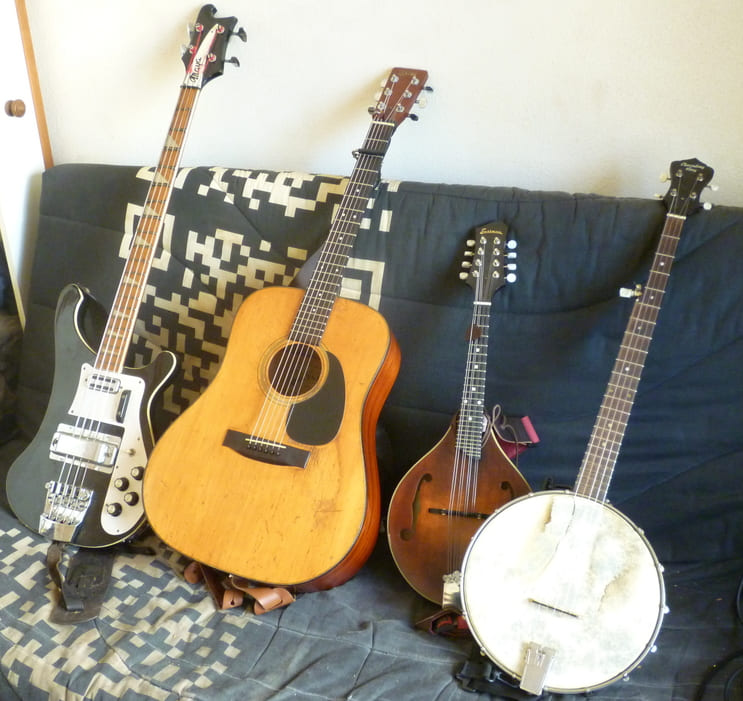 Instruments (a bass, an accoustic guitar, a mandolin and a banjo) sitting on a couch