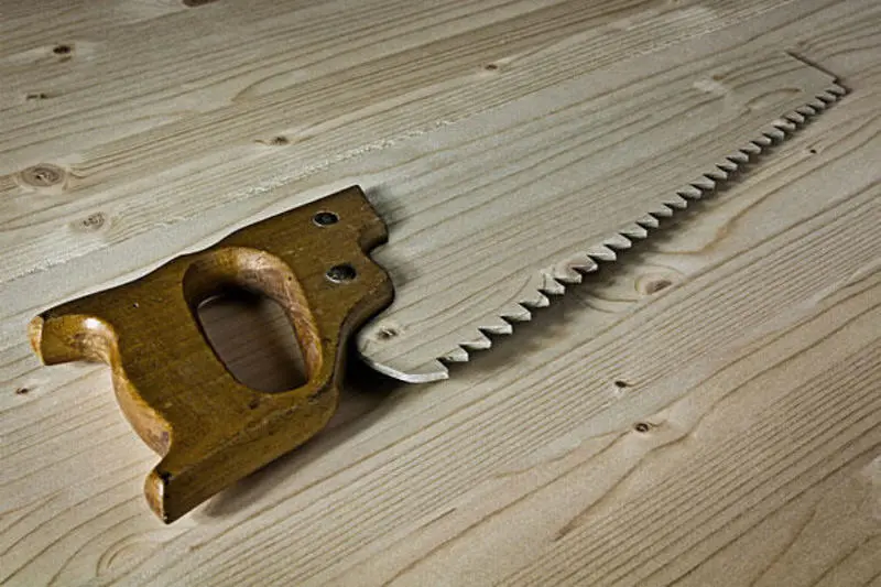 Wooden saw lying on a wooden surface